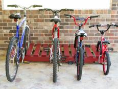 bikes lined up on a red wooded bike rack.